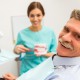 Older gentleman patient in dental practice with hygenist shoing how to brush dentures