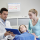dentist and parent in exam room looking at an ipad as the child lays in the chair